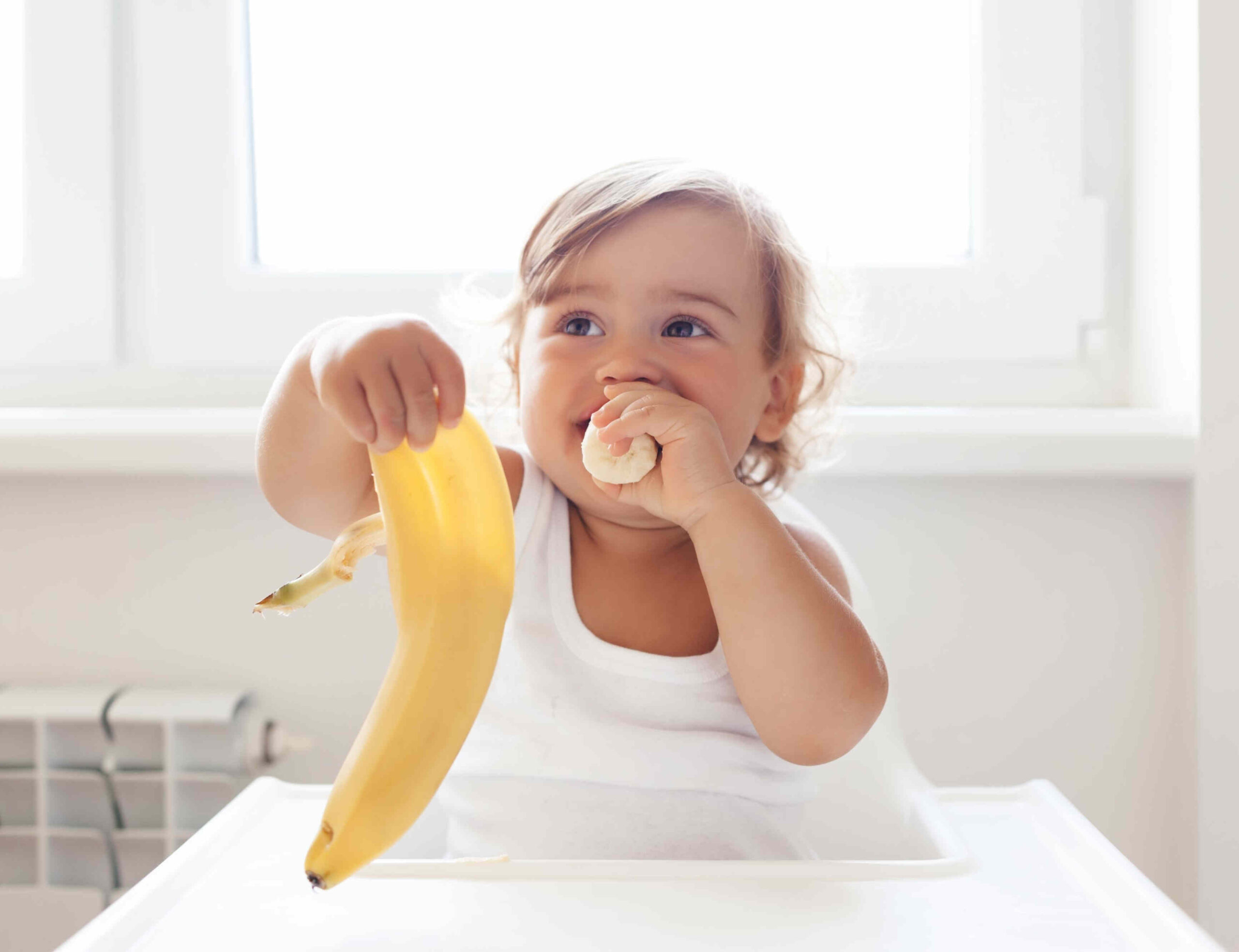 baby eating banana scaled